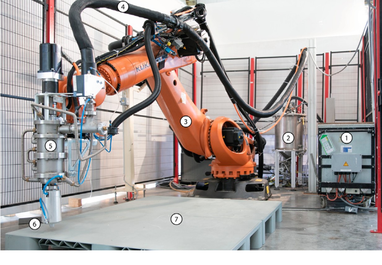 Photograph of the Wax Foam 3D Printing robotic unit, showing the industrial robot, extrusion apparatus, material-processing equipment, and printing bed.